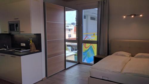 ein Schlafzimmer mit einem Bett und eine Küche mit einem Balkon in der Unterkunft 211 Amsterdam, Studio Apartment, 30m2 1-4 Pers in Klagenfurt am Wörthersee