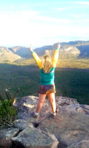 a woman standing on a rock with her arms in the air at Casa Verde na Chapada Diamantina in Palmeiras
