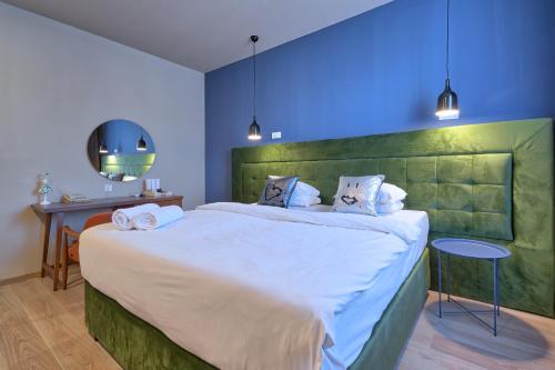 Schlafzimmer mit einem großen Bett mit einem grünen Kopfteil in der Unterkunft Boutique Hotel St Georgije in Banja Luka