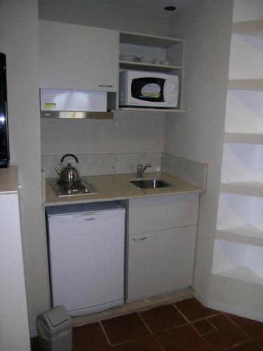 a small kitchen with a sink and a microwave at Costa Carilo Apart de Mar By HS in Carilo