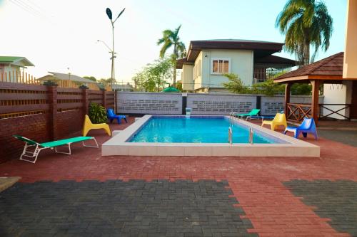 a swimming pool with chairs and a house at Riando appartement Royal Rainville in Paramaribo