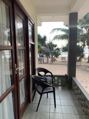 a patio with two chairs and a table on a porch at Mirage Beach House at Morava Court in Hikkaduwa