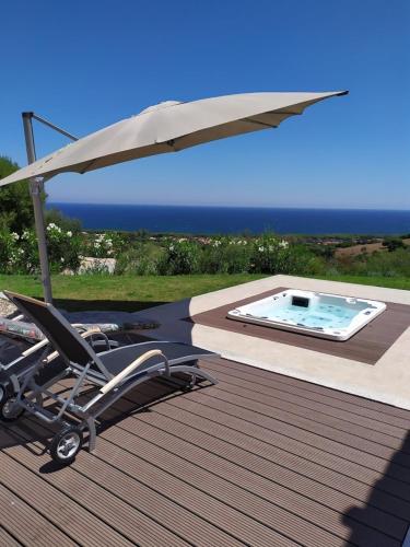a chair under an umbrella next to a swimming pool at Residence Il Borgo Del Mare - BUDONI SWEET HOME in Budoni