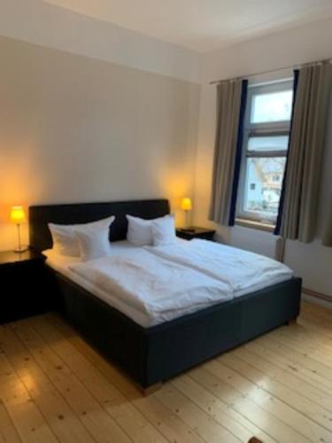 ein Schlafzimmer mit einem Bett mit weißen Laken und einem Fenster in der Unterkunft Appartment 5 in Braunlage