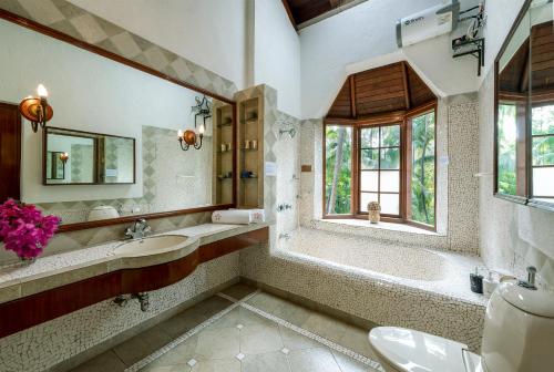 阿利巴格的住宿－SaffronStays Thalassea, Alibaug - picturesque sea-facing villa with colonial decor，一间带水槽和浴缸的浴室以及窗户。