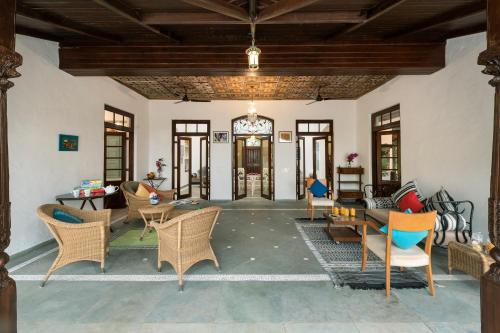 a living room with wicker chairs and tables at SaffronStays Thalassea, Alibaug - picturesque sea-facing villa with colonial decor in Alibaug