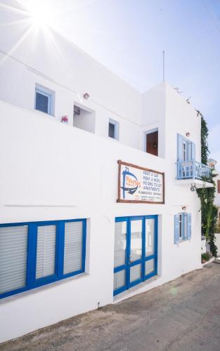 a white building with blue windows and a sign at Podotas Group in Kamarai