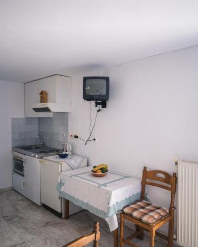 a kitchen with a table and a tv on the wall at Podotas Group in Kamarai