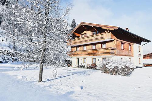una gran casa de madera en la nieve con un árbol en Appartements Oberhof, en Flachau