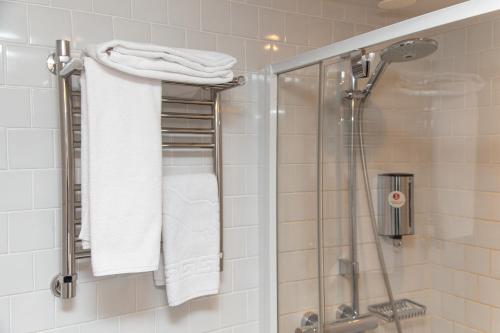 a bathroom with a shower with white towels at AZIMUT City Hotel Murmansk in Murmansk