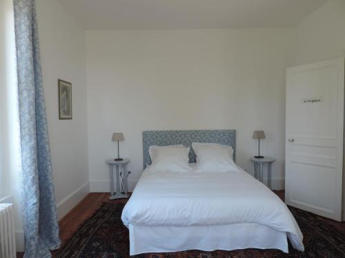 a bedroom with a white bed with two tables at Chambres d'Hôtes de la Bucaille in La Bucaille