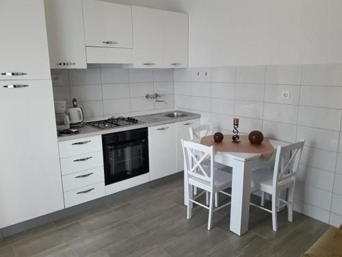 una cocina blanca con mesa y sillas. en Delfin Apartments, en Sveti Juraj