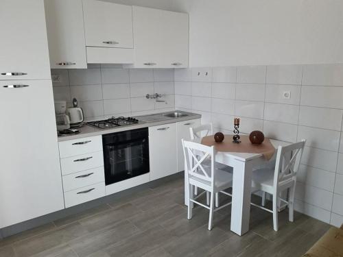 a white kitchen with a table and chairs in it at Delfin Apartments in Sveti Juraj