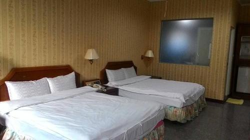 a hotel room with two beds and a television at 雲林東勢御花園汽車旅館 in Dongshi