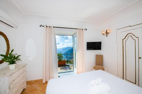 a white bedroom with a bed and a window at Ville Olimpo in Positano