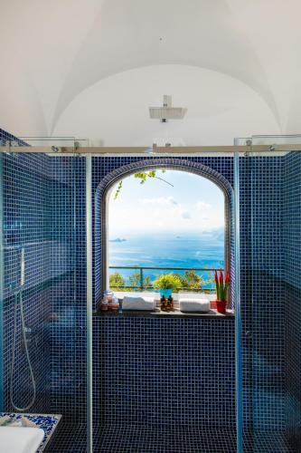 a bathroom with a glass shower with a window at Ville Olimpo in Positano