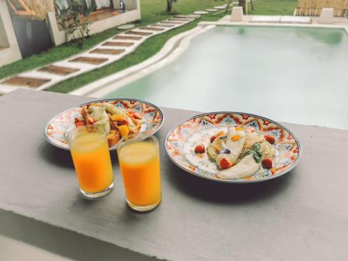 two plates of food and two glasses of orange juice at Capila Villa Bali in Canggu