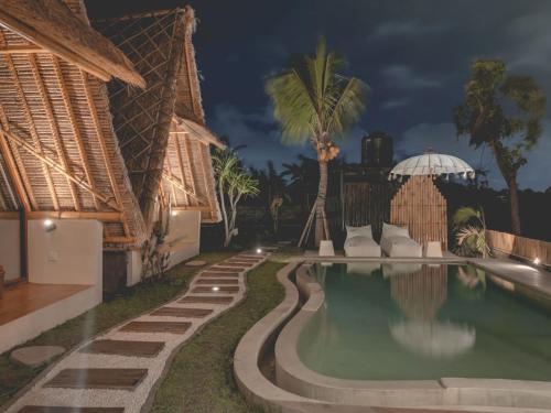 a swimming pool with a palm tree next to a building at Capila Villa Bali in Canggu