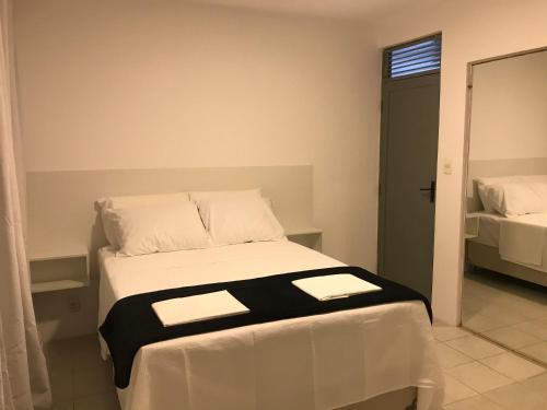 a bedroom with a white bed with black and white sheets at Apt localização excelente in Maceió