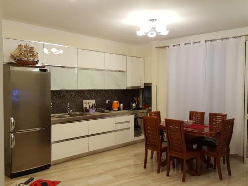 a kitchen with a table and a stainless steel refrigerator at Holiday Center Apartment in Shkodër