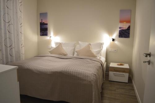 a bedroom with a bed with white sheets and pillows at Ferienwohnung MeerZeitPerle in Glowe