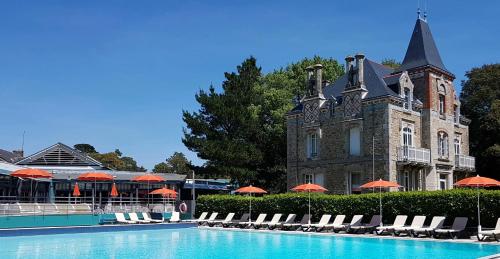 a building with a swimming pool with chairs and umbrellas at Résidence Ker Juliette in Pornichet