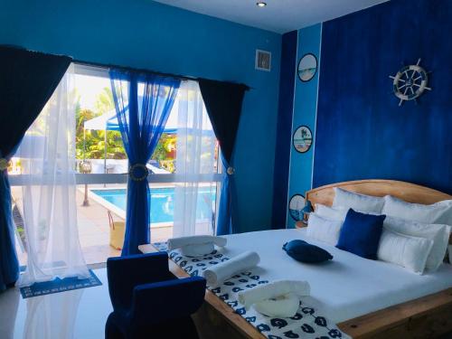 a bedroom with a bed with blue walls and a window at Petite Flower Guest House in Talata-maty