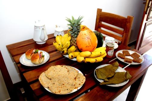 a wooden table topped with plates of food and fruit at Verona D' Oro in Dickwella