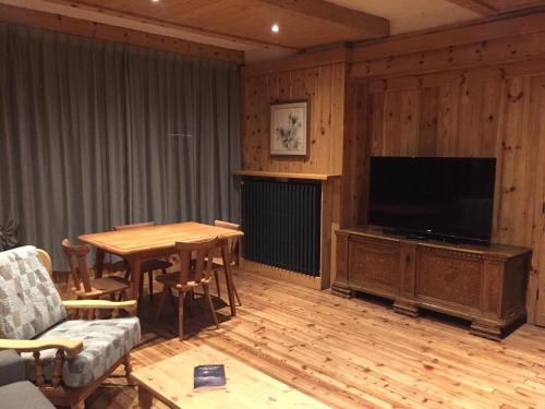a living room with a table and a flat screen tv at Appartamenti De Betta in Sappada