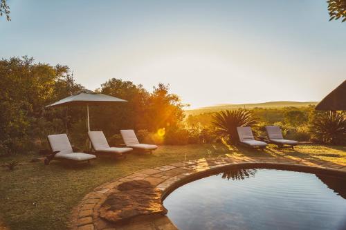 a backyard with a pool with chairs and an umbrella at Jembisa Bush Home in Melk River