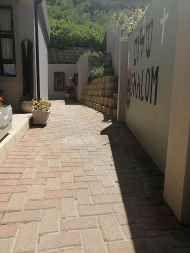 a brick walkway with a shadow on the side of a building at Froggy at the Pond in Simonʼs Town