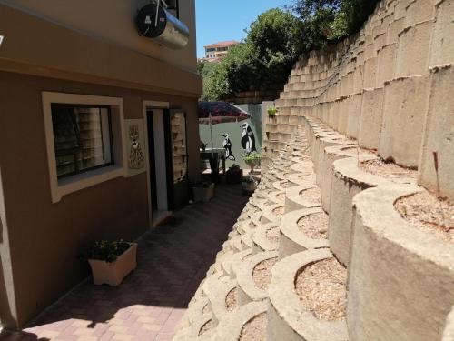 a stone retaining wall next to a building at Froggy at the Pond in Simonʼs Town