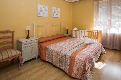 ein Schlafzimmer mit einem Bett und einem Stuhl in der Unterkunft Apartamentos turisticos Avila Villa Carmen III in Avila