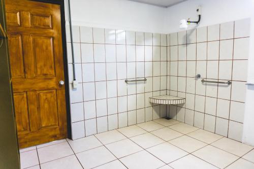 a tiled bathroom with a toilet and a wooden door at Cabinas EL PRADO in San Isidro