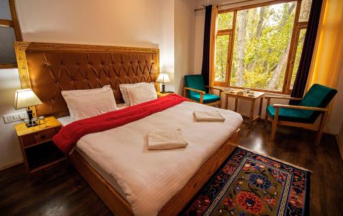 a bedroom with a large bed with two chairs and a window at Tushita Ladakh in Leh