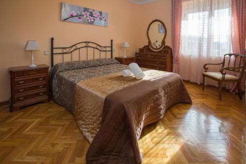 a bedroom with a bed and two dressers and a mirror at Apartamentos Turisticos Avila Villa Carmen II in Avila