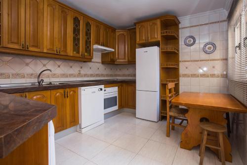 a kitchen with wooden cabinets and a white refrigerator at Apartamentos Turisticos Avila Villa Carmen II in Avila