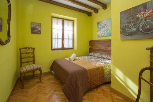 1 dormitorio con paredes amarillas, 1 cama y ventana en Apartamentos turisticos Avila Villa Carmen I, en Ávila