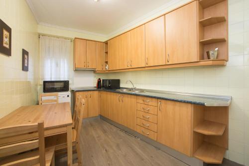 a kitchen with wooden cabinets and a wooden table at Apartamentos turisticos Avila La Catedral in Avila