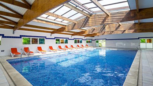 una piscina cubierta con sillas naranjas y una gran piscina en APPART - T3 - 6 PERSONNES – GOLF CAP D’AGDE, en Cap d'Agde