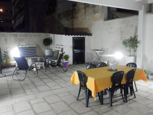 a table with chairs and a yellow table cloth at Casa Lauretta - terrazza con idromassaggio - garage wifi e bici gratuite in Lecce