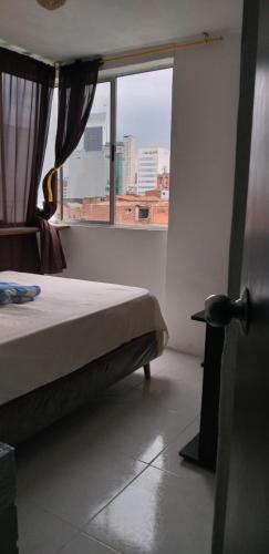 a bedroom with a bed and a large window at CENTRO! San Lorenzo - Downtown - Apto con 2 Hab & Parqueadero in Medellín