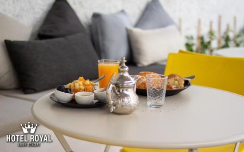 a table with a plate of food and orange juice at Hôtel Royal Urban Concept in Fez