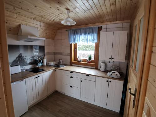 uma cozinha com armários brancos e uma janela em Domek u Marysi em Zakopane