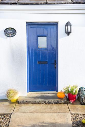 a blue door on a white house with pumpkins at Blue Sky Cottage, Doolin in Carrowauff