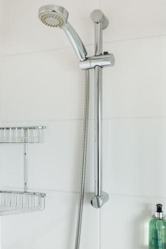 a chrome shower head in a white bathroom at Blue Sky Cottage, Doolin in Carrowauff