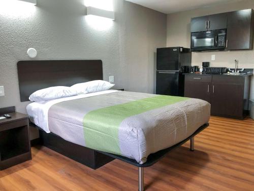 a bedroom with a large bed and a kitchen at Studio 6 Wichita, KS - Airport in Wichita