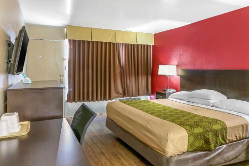 Habitación de hotel con cama y pared roja en Econo Lodge, en Shorewood