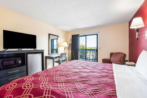 a hotel room with a bed and a flat screen tv at Econo Lodge Waynesville in Waynesville