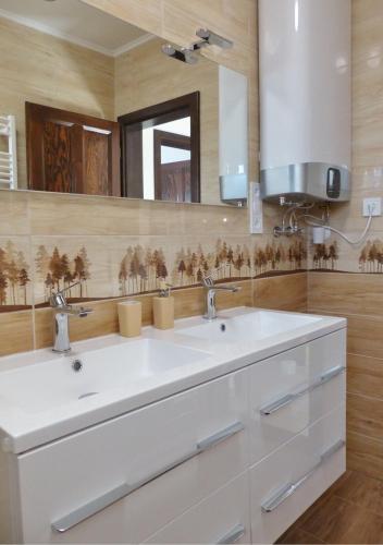 a bathroom with two sinks and a large mirror at Guest House Magyarlukafa in Magyarlukafa